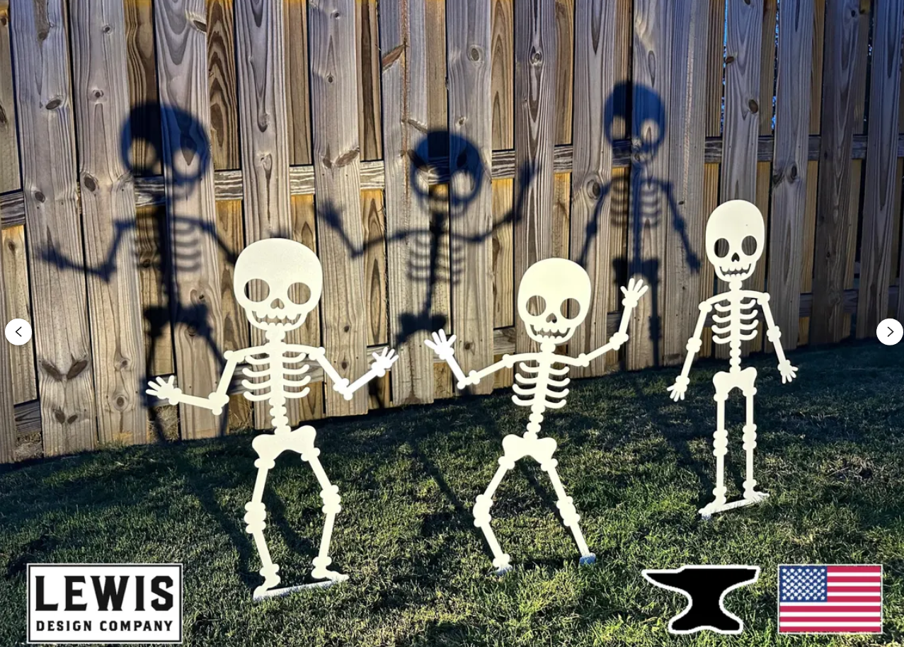 Cute Spooky Halloween White Metal Skeleton Yard Stakes casting shadow on wooden fence behind them