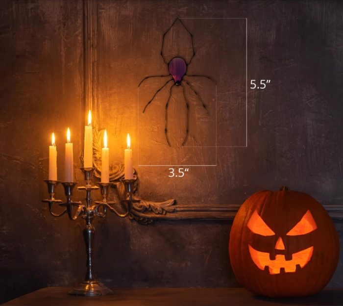 Hanging purple stained glass spider on the wall next to a candelabra and jack o'lantern