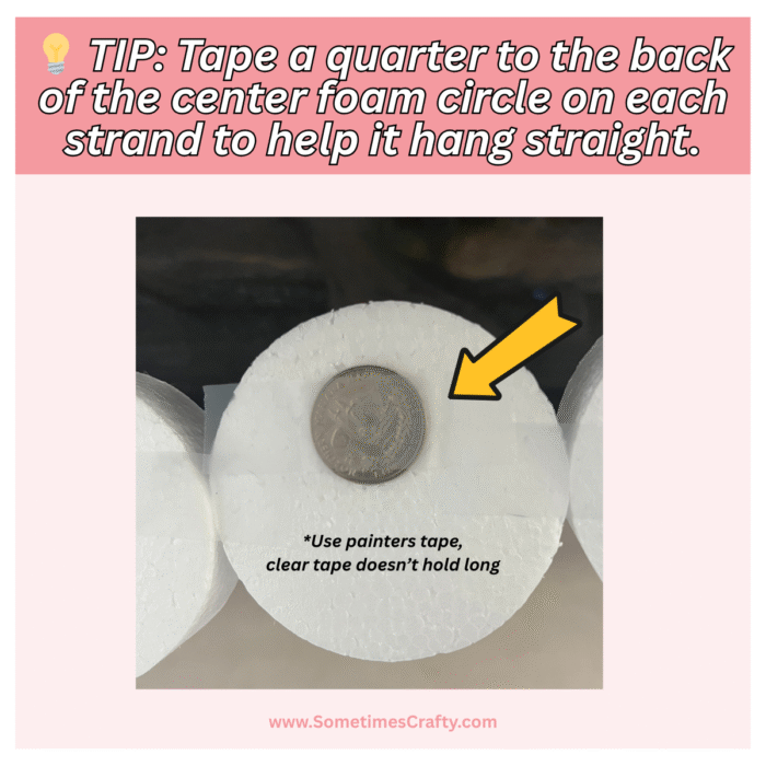 Close-up of a DIY banner hack using a quarter taped to a foam circle to help it hang straight,